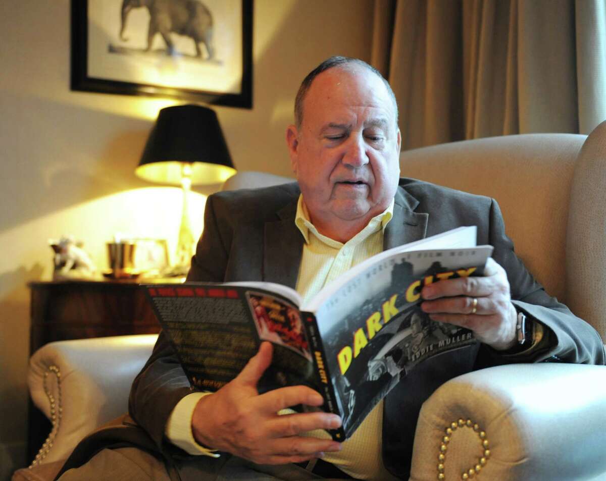 Film noir expert Michael Kovner pages through a film noir book in his home in Greenwich.