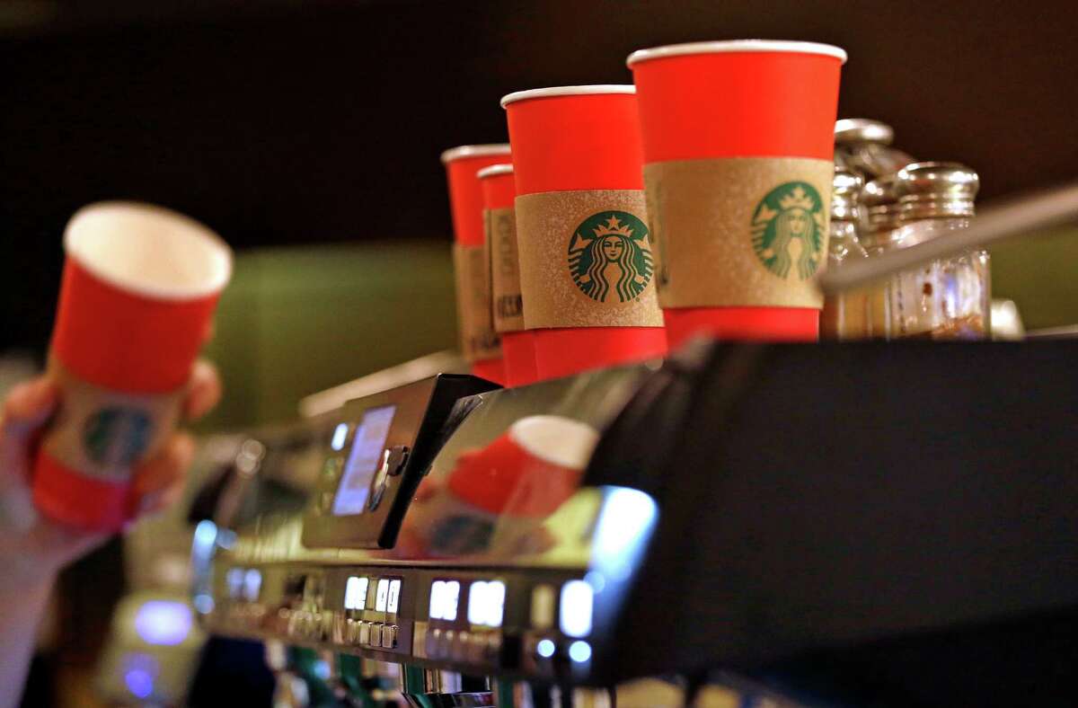 A barista reaches for a red paper cup as more, with cardboard liners already attached, line the top of an espresso machine at a Starbucks coffee shop in the Pike Place Market, Tuesday, Nov. 10, 2015, in Seattle. 