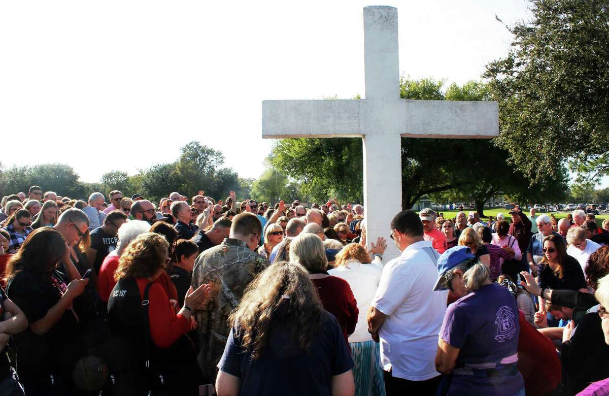 A group gathers around the cross for prayer at Riverfront Park in Port Neches during a vigil on Sunday.