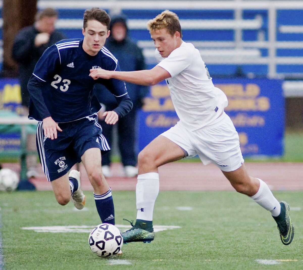 Wilton High School's Daniel Jensen tries to get the ball before New Milford High School's Dimitri Lambropoulos gets away in the Class LL game at Brookfield High School. Thursday, Nov. 12, 2015
