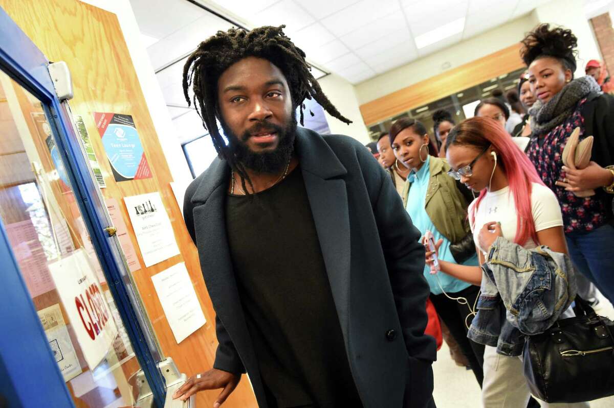 Jason Reynolds of Brooklyn, an award-winning writer of young adult books, center, walks though the hallway on Tuesday, Nov. 17, 2015, at Albany High in Albany, N.Y. Reynolds was at the high school to share his books and life story to student. (Cindy Schultz / Times Union)