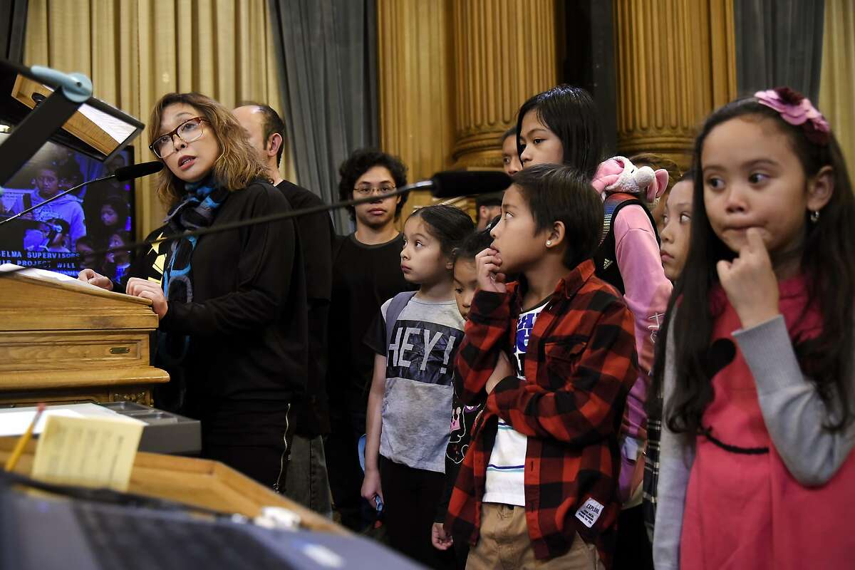 Executive director of West Bay Pilipino Vivian Zalvidea Araullo, left, stands with Filipino youth from her program as she speaks against the 5M project during a board of supervisors meeting at City Hall in San Francisco, CA Tuesday, November 17 2015.