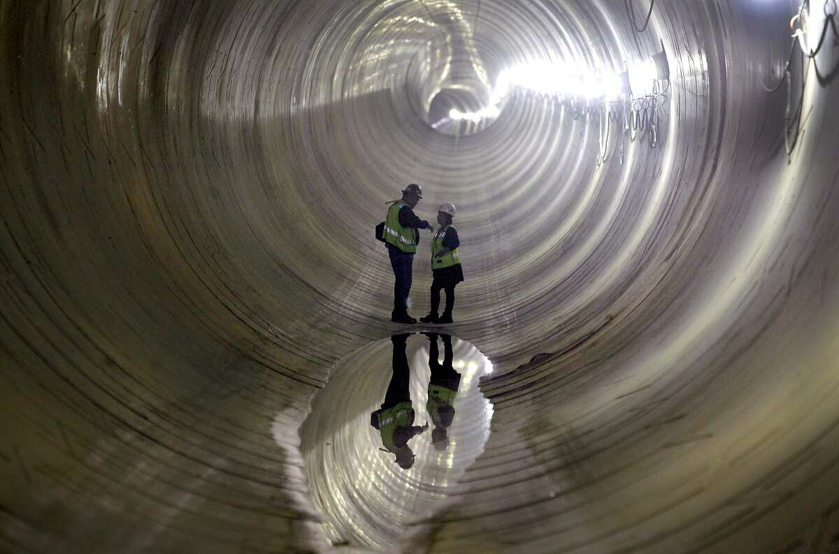Program Safety Manager Jeff Kraus confers with Janis Yuen, the Central Subway project's community outreach coordinator, at the lowest point of the northbound tunnel below Fourth Street in San Francisco, Calif. on Tuesday, Nov. 17, 2015. Water which has accumulated from a cleaning project is being pumped to the surface.