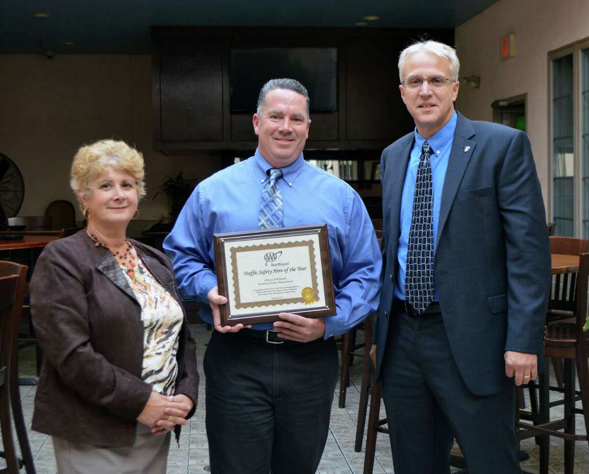 Stamford police officer Jeffrey Booth, center, receiving the Traffic Safety Hero Award from AAA Public Affairs Manager Fran Mayko, left, and Assistant Stamford police Chief Tom Wuennemann, right.
