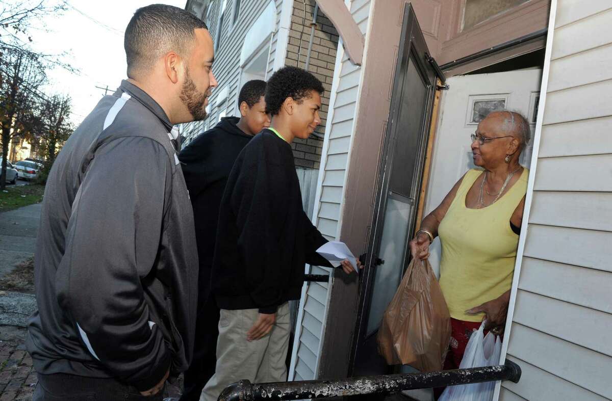 Green Tech High Charter School principle Paul Miller, left, with two ninth grade students Steven Vaughn, center, and Kijaveon Serrano drop off food for a complete Thanksgiving dinner to a woman on North Manning Boulevard on Friday Nov. 20, 2015 in Albany, N.Y. (Michael P. Farrell/Times Union)