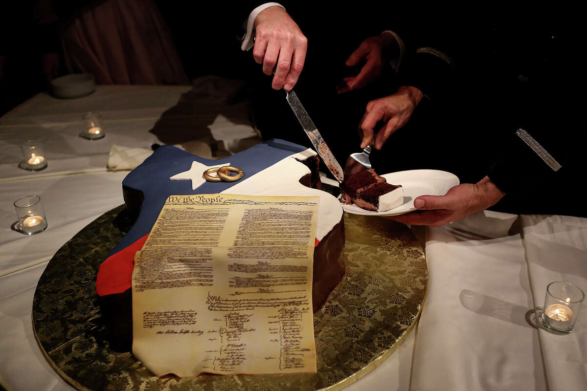 Phariss and Holmes cut one of their two wedding cakes, made in the shape of Texas and adorned with an image of the U.S. Constitution.