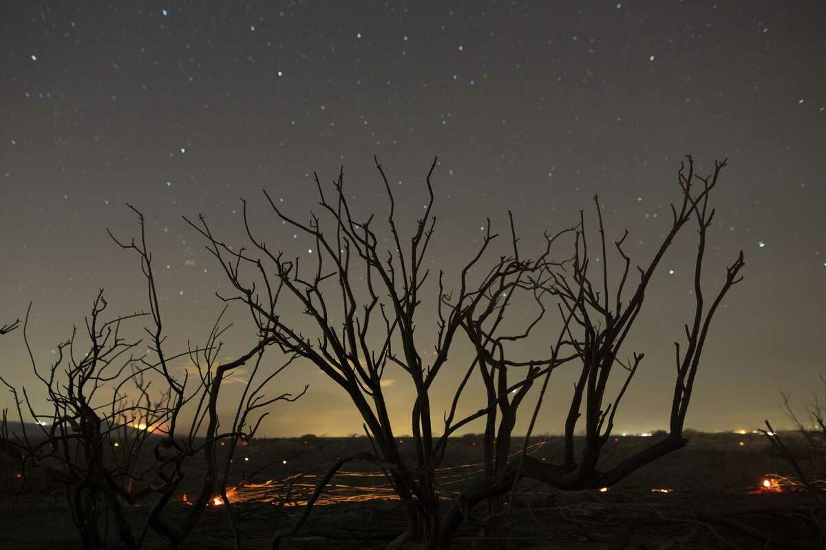 VICTORVILLE, CA - JULY 18: Stars shine over a landscape of embers burning in the wake of the North Fire, which caused people to abandon their vehicles and flee as flames jumped the 215 freeway in the early morning hours of July 18, 2015 near Victorville, California.