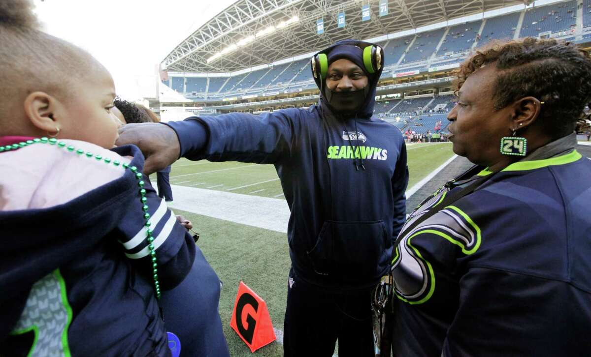 Seattle Seahawks running back Marshawn Lynch, center, looks at his god-daughter, Lauren Hall-Lynch, left, as his mother, Delisa "Mama Lynch" Lynch, right, looks on before an NFL football game against the San Francisco 49ers, Sunday, Nov. 22, 2015, in Seattle.