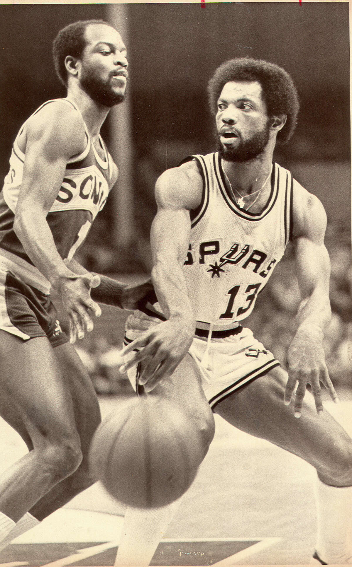 James Silas of the Spurs makes a pass around Seattle’s Gus Johnson during a late 1970s game at HemisFair Arena.