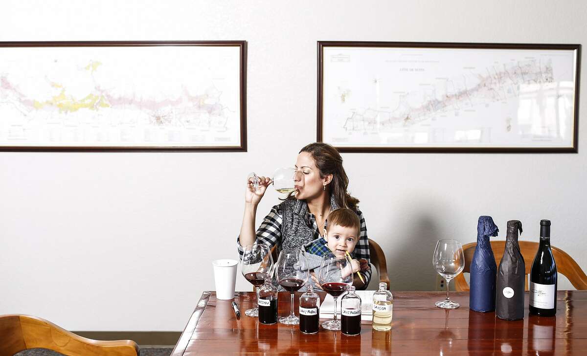 Bibiana Gonzalez-Rave of Cattleya wines tastes her Cattleya 2015 Chardonnay, Pratt Vineyard while holding her son, Lucas Richard Pisoni, on Tuesday, Nov. 24, 2015 in Santa Rosa, Calif.