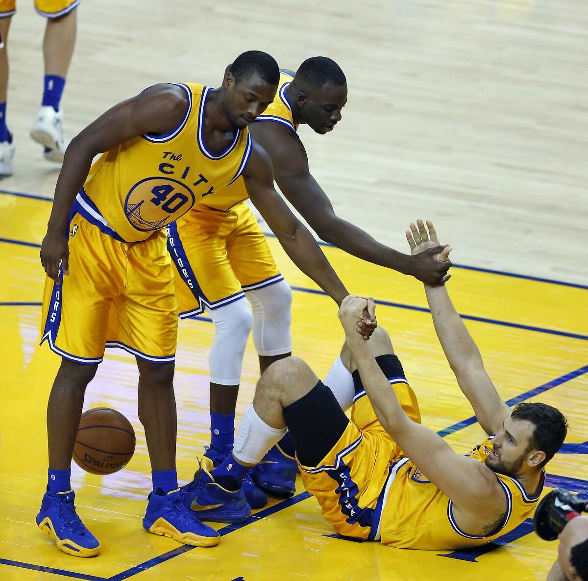 Golden State Warriors' Andrew Bogut is helped up by Harrison Barnes and Draymond Green in 3rd quarter against Los Angeles Lakers during NBA game at Oracle Arena in Oakland, Calif., on Tuesday, November 24, 2015.