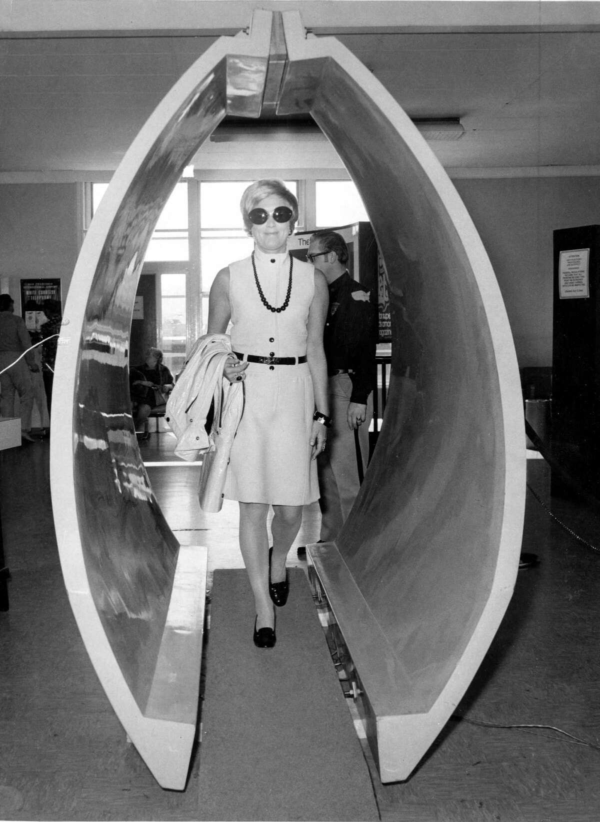 Mrs. Donald Pritzker walks through a metal detector as part of a security check at San Francisco International Airport in 1973.