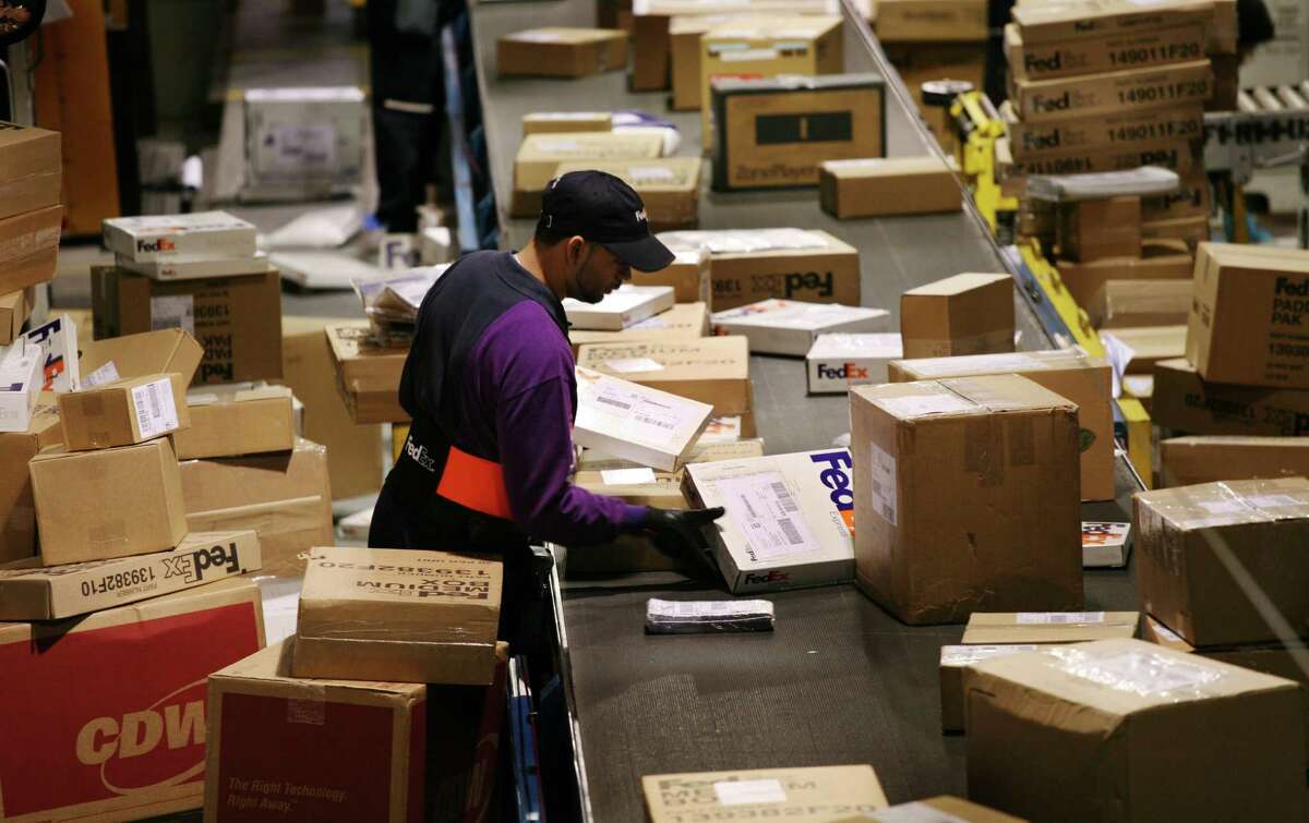 File - A FedEx driver picks packages for his delivery route from a conveyor belt in a distribution facility on Thursday, Dec. 13, 2007 in New York. (AP Photo/Mark Lennihan)