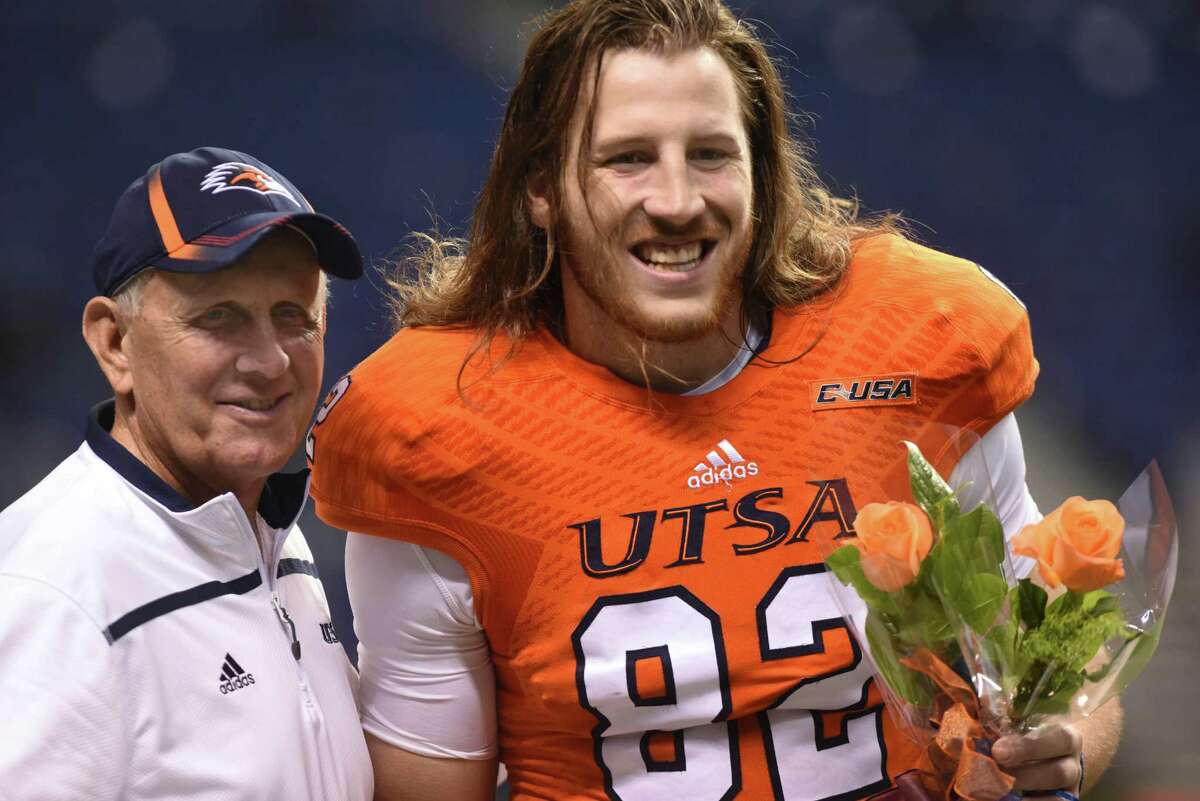 UTSA senior tight end David Morgan II carries flowers as he stands with coach Larry Coker before the team’s game against Middle Tennessee State in college football action in the Alamodome on Nov. 28, 2015.