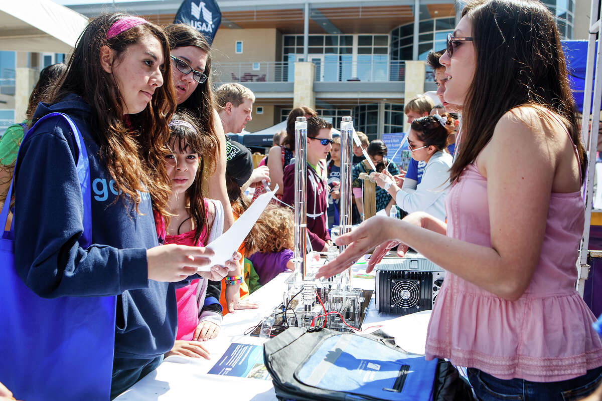 Audrie Cabrera (right) with St. Phillips College talks to Cianna Garcia, 15, (from left), Serena Garcia, 8, and Lysandra Garcia, 16, about the school's STEM — Science Technology, Engineeering and Math — program during the Girls Inc. of San Antonio's 7th annual Rockit into The Future Science Festival presented by Rackspace Hosting on April 6, 2013.