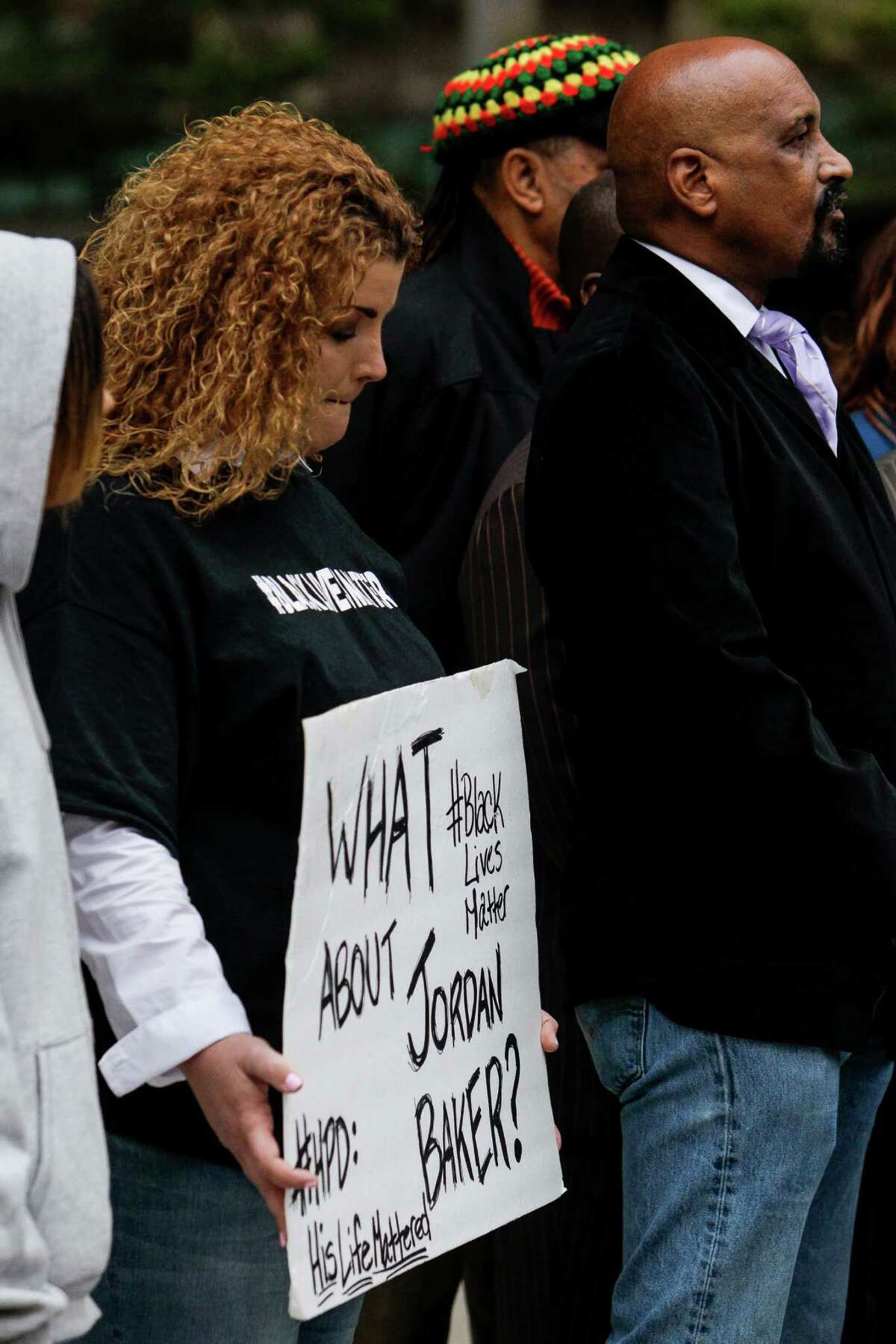 Shere Dore, left, holds a sign as activist Deric Muhammad holds a press conference with other members of the black community to demand the Houston Police Department release a video of the Jordan Baker arrest video Monday, Nov. 30, 2015, in Houston.