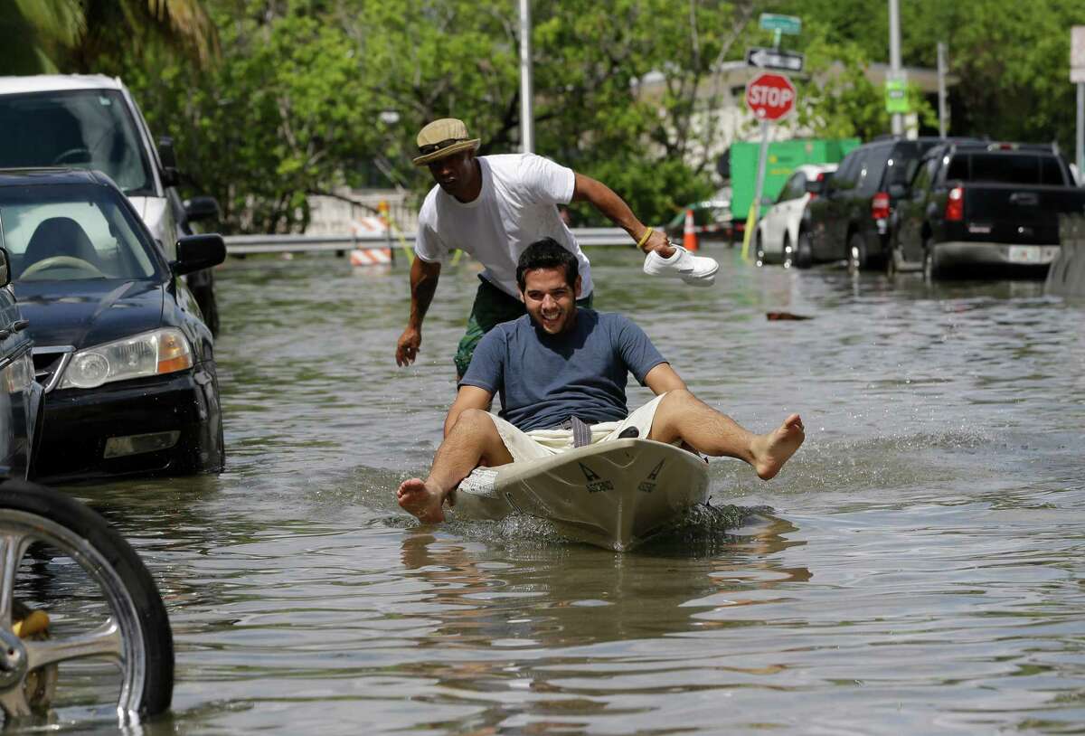 Juan Carlos Sanchez, rear, pushes Jose Silva, Jr. in a kayak on a flooded street near Collins Ave., Wednesday, Sept. 30, 2015, in Miami Beach, Fla. The street flooding was in part caused by high tides due to the lunar cycle, according to the National Weather Service. (AP Photo/Lynne Sladky)