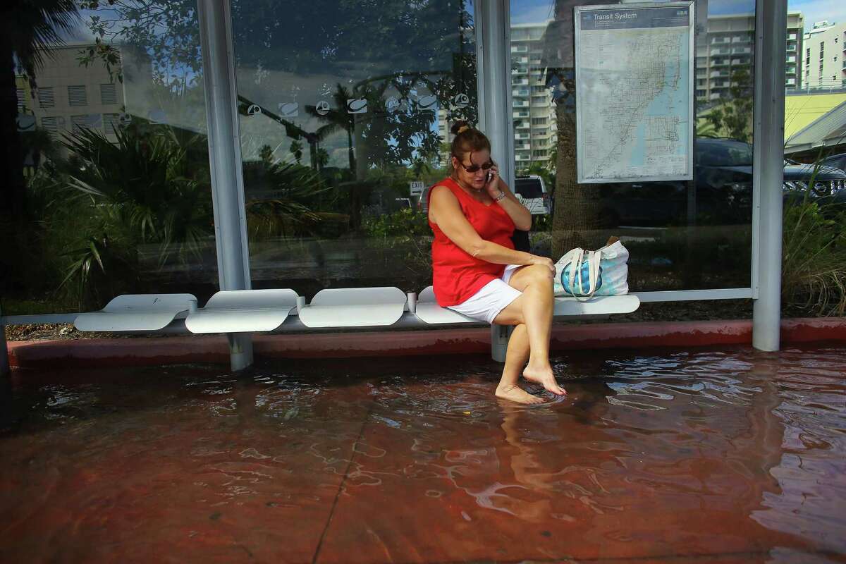 MIAMI BEACH, FL - OCTOBER 18: Cindy Minnix waits for a bus in a flooded street near where protesters were calling on the presidential candidates to talk about their plans to fight climate change on October 18, 2012 in Miami Beach, Florida. Some of the streets on Miami Beach are flooded due to unusually high tides that the protesters felt are due to rising seas, which are connected to global warming and climate change. Published reports indicate that Florida ranks as the most vulnerable state to sea-level rise, with some 2.4 million people, 1.3 million homes and 107 cities at risk from a four-foot rise in sea levels. (Photo by Joe Raedle/Getty Images)