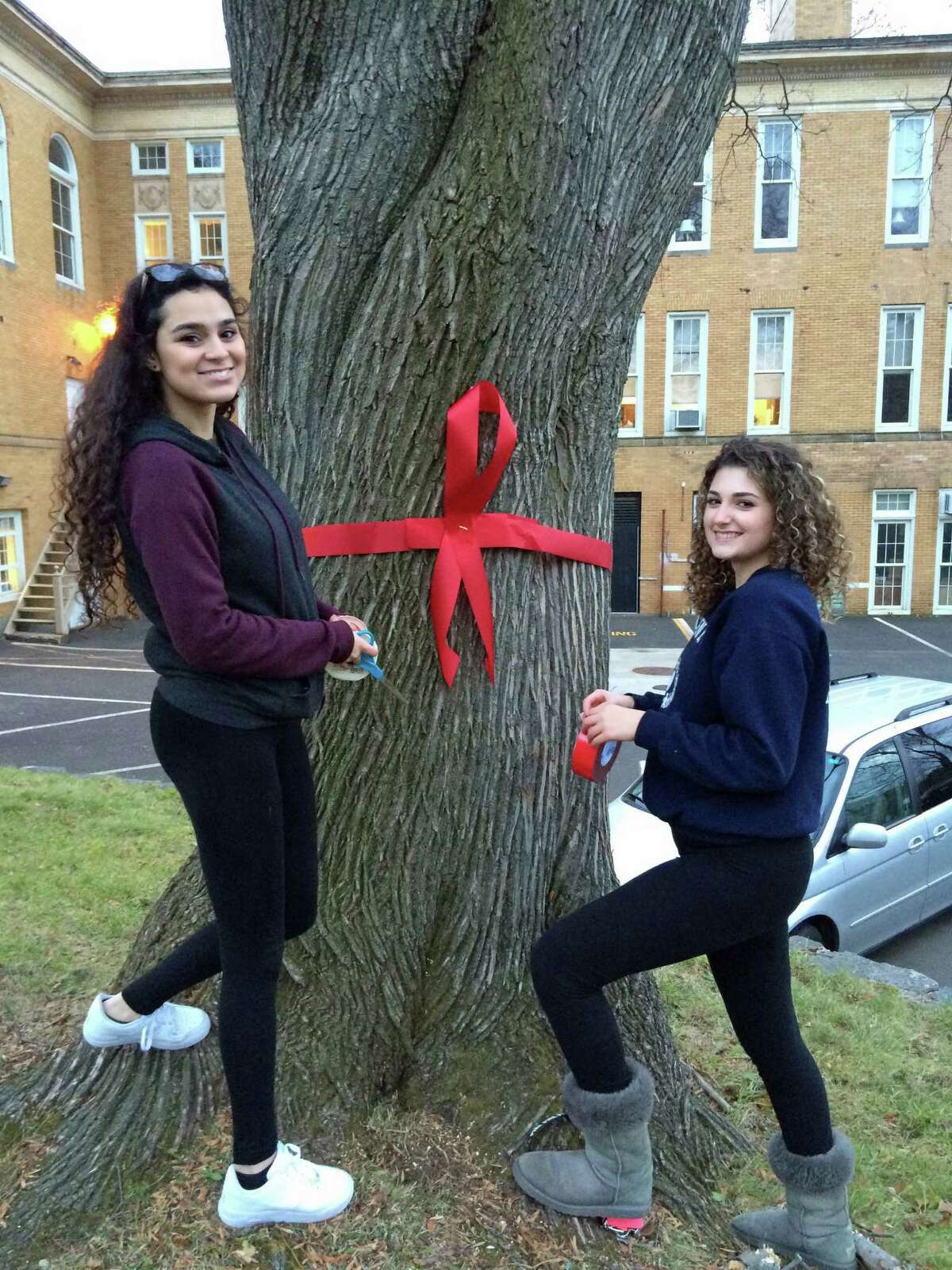 Amanda Silva and Julia Fama, peer educators, help put up ribbons on Greenwich Avenue for World AIDS Day.