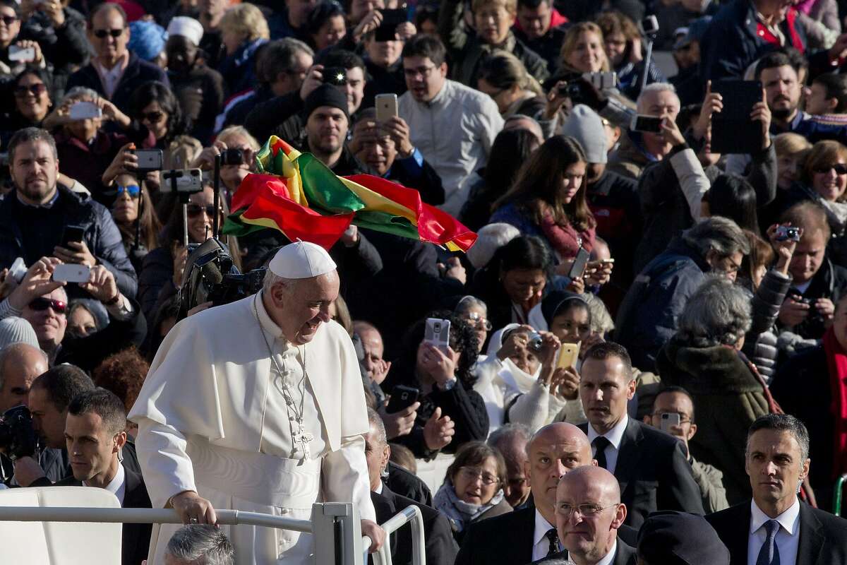 A flag is tossed in the air as Pope Francis arrives for his weekly general audience in St. Peter's Square at the Vatican, Wednesday, Dec. 2, 2015. (AP Photo/Alessandra Tarantino)