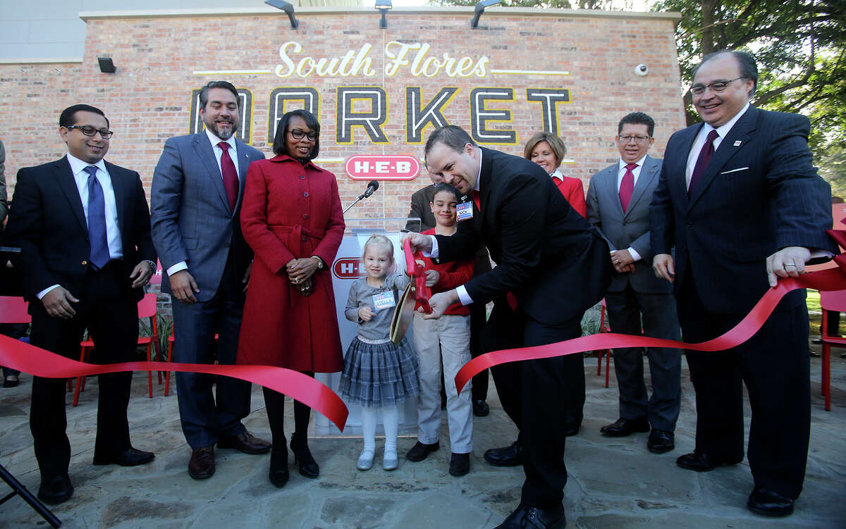 Nick George (right, center, holding scissors), store director at the new South Flores H-E-B Market store, cuts the ribbon at opening ceremonies with his daughter Stella,3, (center) and son Sutton,6. The new South Flores H-E-B Market store at the corner of Cesar Chavez and South Flores in downtown San Antonio, Texas opened at 7:00 a.m. Wednesday December 2, 2015. Standing next to George's daughter (wearing red coat) is San Antonio mayor Ivy Taylor.