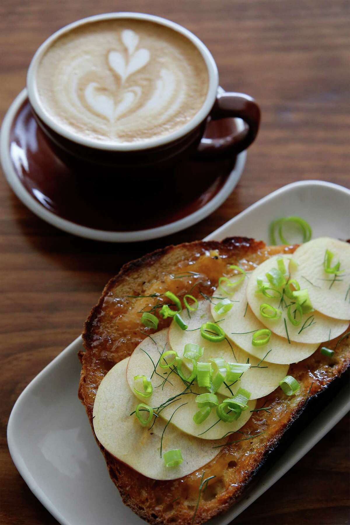 The Fairview Coffee Bar and Grub offers customers their seasonal house-baked sourdough bread toasted and prepared with sharp cheddar, Hot Apple Pie jam, honey crisp apple slices, fennel and green onion served with alongside a cup of cappuccino.