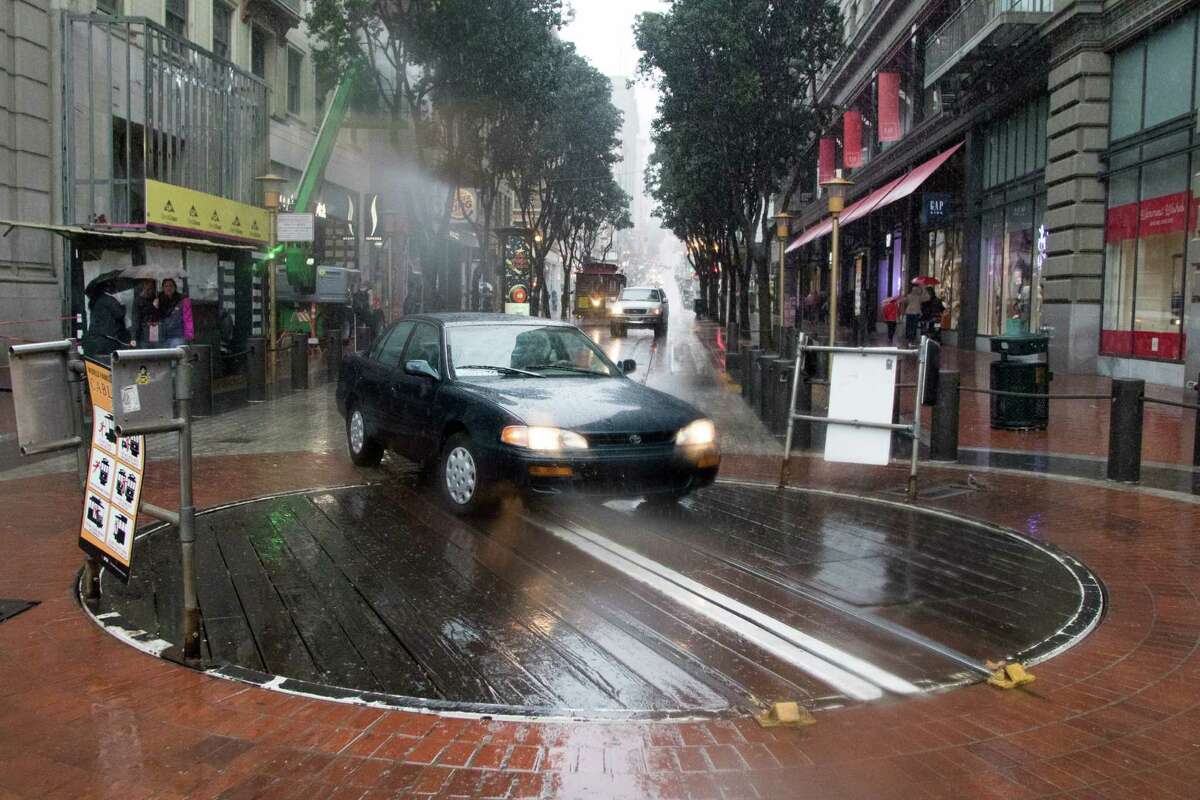 A car drove around a cable car and onto the Powell Street turnaround platform during the rainstorm in San Francisco on Thursday, Dec. 3, 2015.
