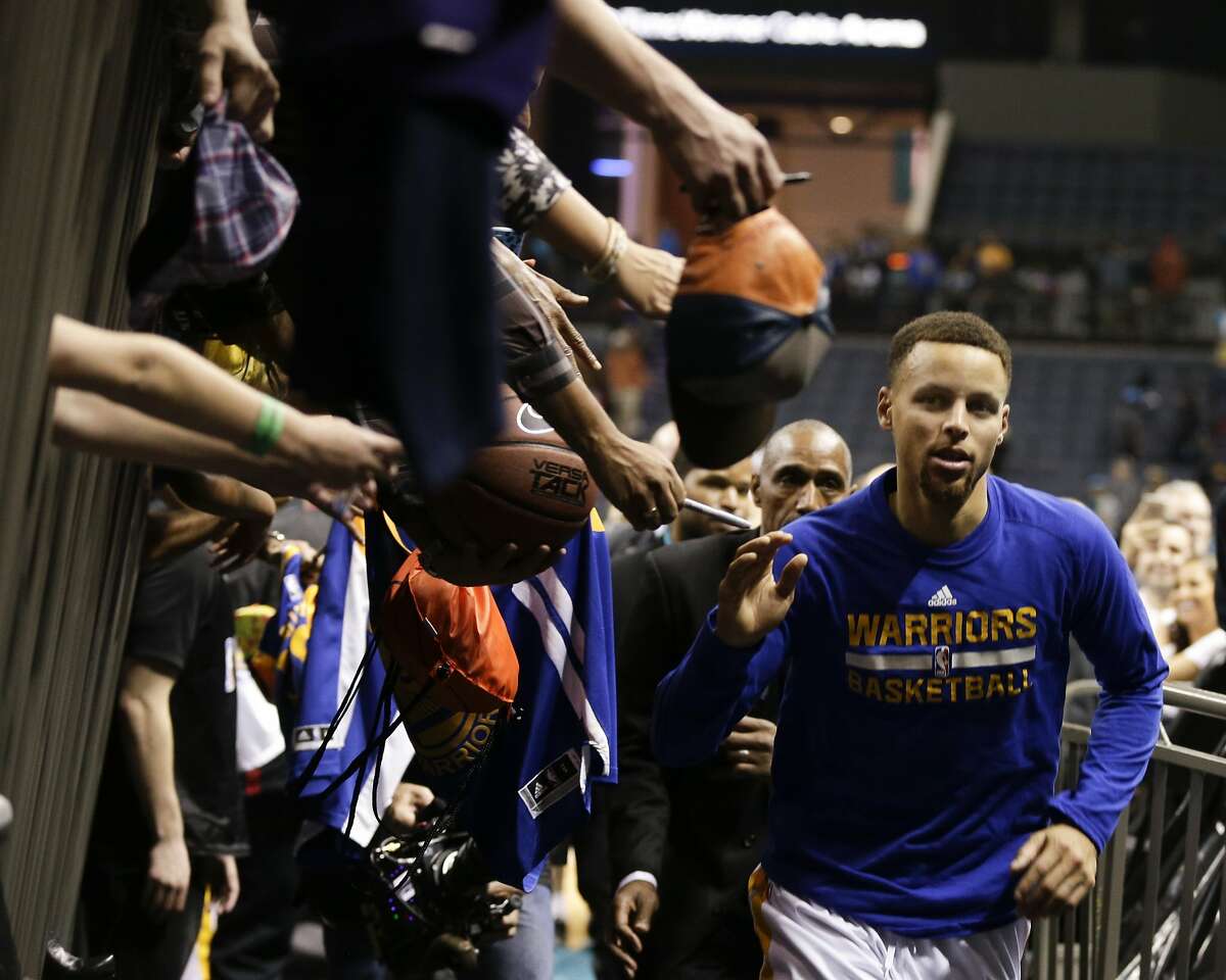 Golden State Warriors guard Stephen Curry runs past fans reaching for him after scoring 40 points as the Warriors defeat the Charlotte Hornets in an NBA basketball game Wednesday, Dec. 2, 2015 in Charlotte, N.C. Golden State won 116-99. (AP Photo/Nell Redmond)