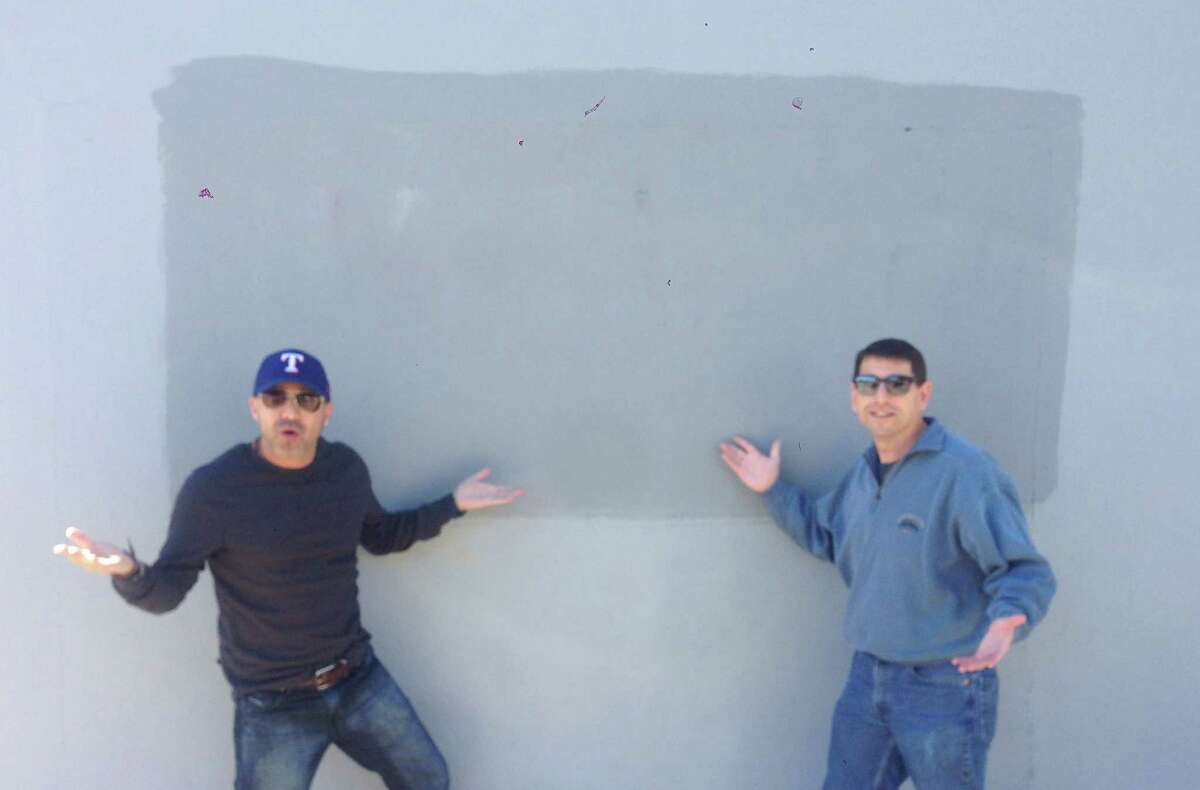 Luis Munoz, left, and Jason Minnix, right, stand where Munoz had created graffiti art with the permission of the business owner at The Pearl. The city of San Antonio painted over the art without letting the business owner know. The art was a popular site for selfies and portraits by residents who came across it.