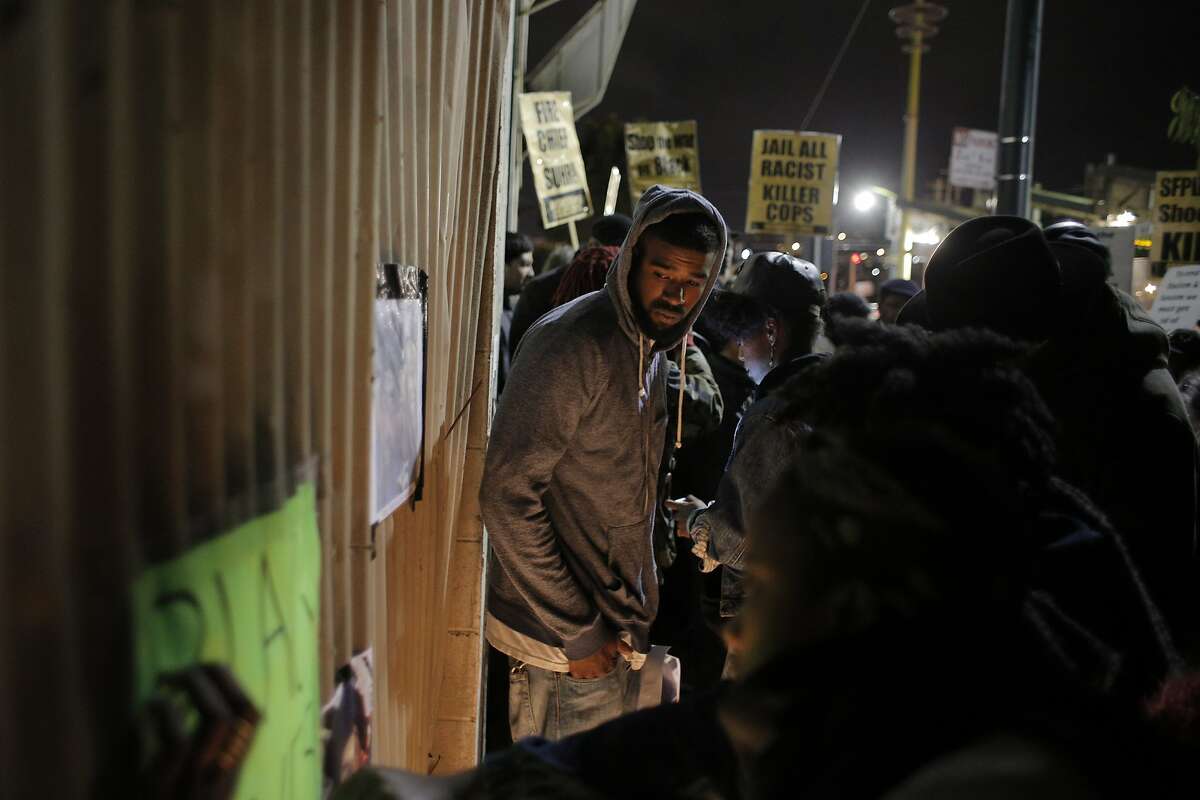 Jeff Stewart looks at an altar built by community members gathered at the site where Mario Woods was shot and killed by San Francisco Police to commemorate the young man in the Bayview district of San Francisco, Calif., on Thursday, December 3, 2015.