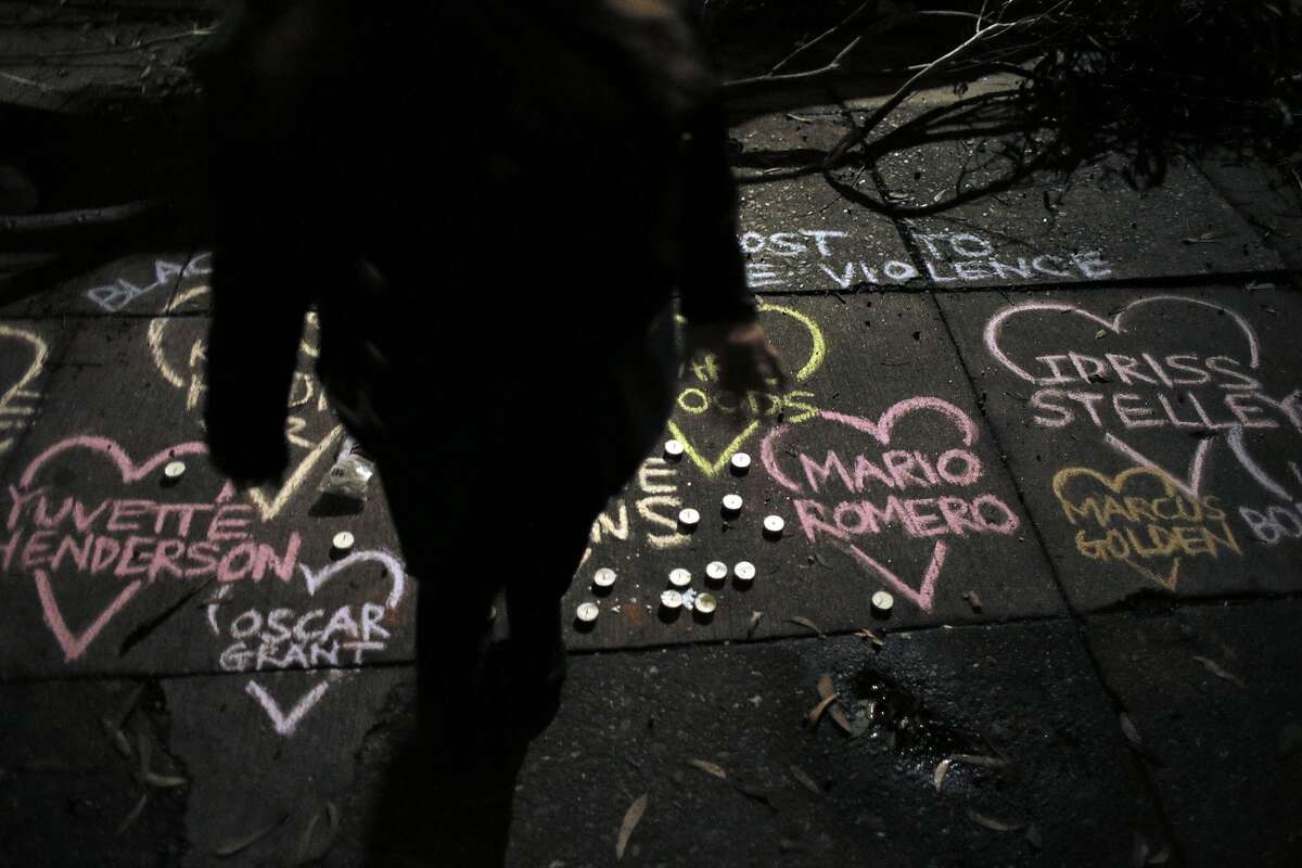 A member of the community stands near chalk art showing the names of those killed by police at the site where Mario Woods was shot and killed by San Francisco Police to commemorate the young man in the Bayview district of San Francisco, Calif., on Thursday, December 3, 2015.
