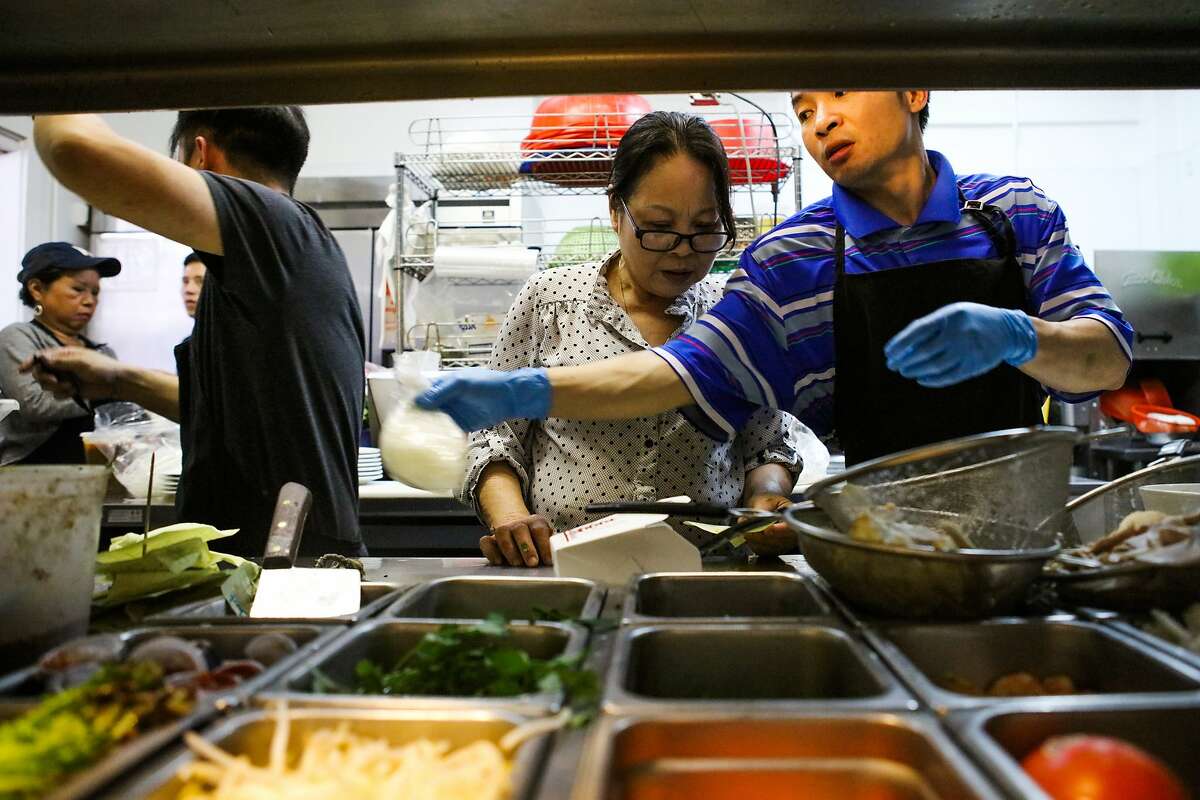 Muoi Au (center) talks to her sons, Dzoung Nguyen (left) and Son Nguyen (right), as they prepare Vietnamese dishes in kitchen of Ha Nam Ninh restaurant in San Francisco, California on Saturday, December 5, 2015.