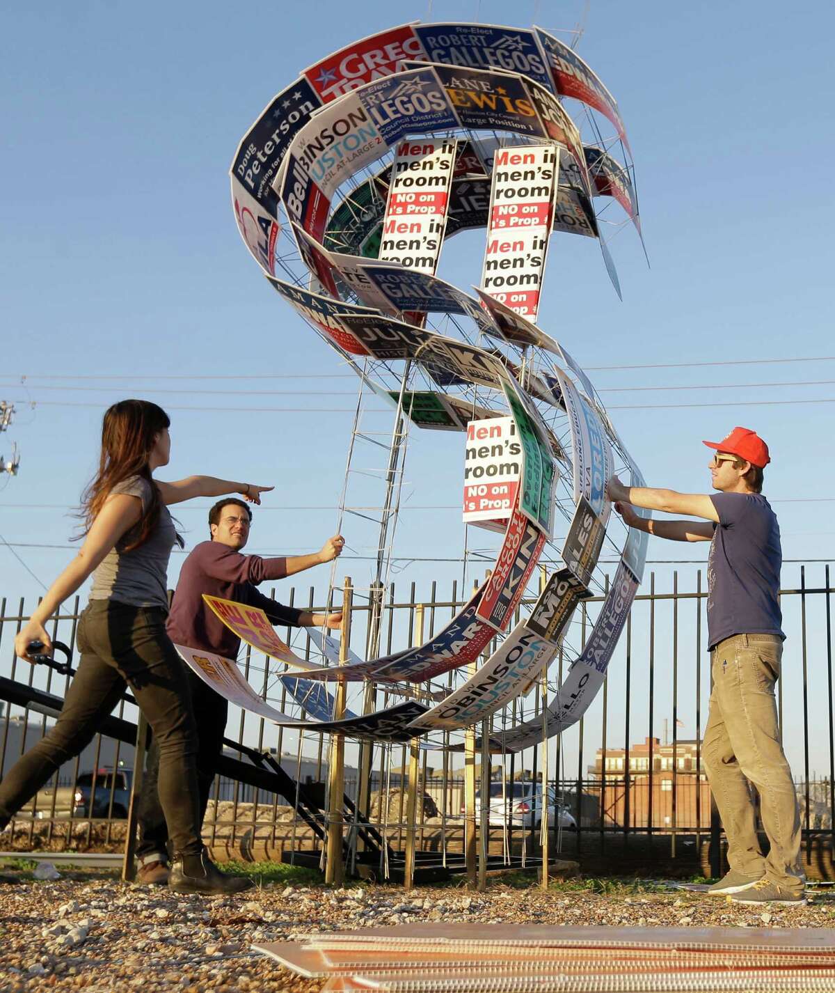 Stephanie Wherry, left, Joshua Fischer, center, and Ted Rubenstein, right, work on building an art installation made from old campaign signs Sunday, Dec. 6, 2015, in Houston. They expect to have the piece on display for Saturday's election.