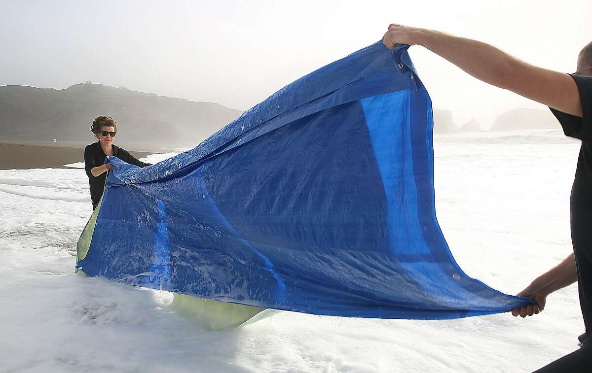 San Francisco photographer Meghann Riepenhoff (left) works with her assistant Simon Wolf (right) on producing abstractions with ocean waves while exposing cyanotype on strathmore bristol paper at Rodeo Beach in Sausalito, California, on Monday, December 7, 2015. Reipenhoff has a solo exhibition called "Littoral Drift" which runs at Camerawork December 10 to February 3.