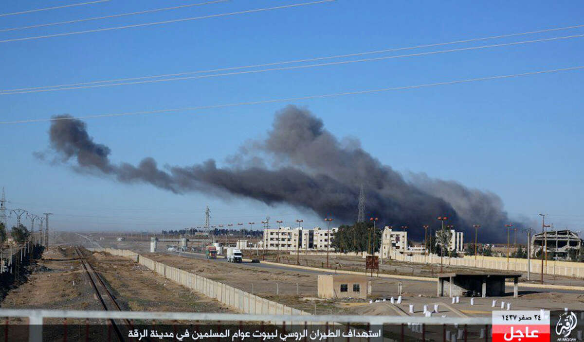 This image posted online Sunday, Dec. 6, 2015, by supporters of the Islamic State militant group on an anonymous photo sharing website, shows smoke rising in the aftermath of an airstrike that targeted areas in Raqqa, Syria. The photo bears the watermark of Islamic State media releases and is consistent with other AP reporting. The Arabic caption on the photo reads, "Russian warplanes target homes of Muslims in Raqqa.â (militant photo via AP)