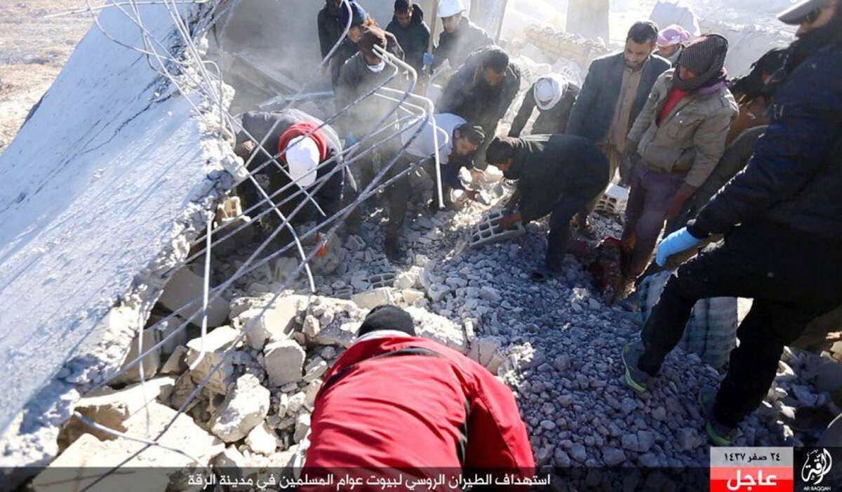 This image posted online Sunday, Dec. 6, 2015, by supporters of the Islamic State militant group on an anonymous photo sharing website, shows Syrians inspecting a damaged building in the aftermath of an airstrike that targeted areas in Raqqa, Syria. The photo bears the watermark of Islamic State media releases and is consistent with other AP reporting. The Arabic caption on the photo reads, "Russian warplanes target homes of Muslims in Raqqa.â (militant photo via AP)