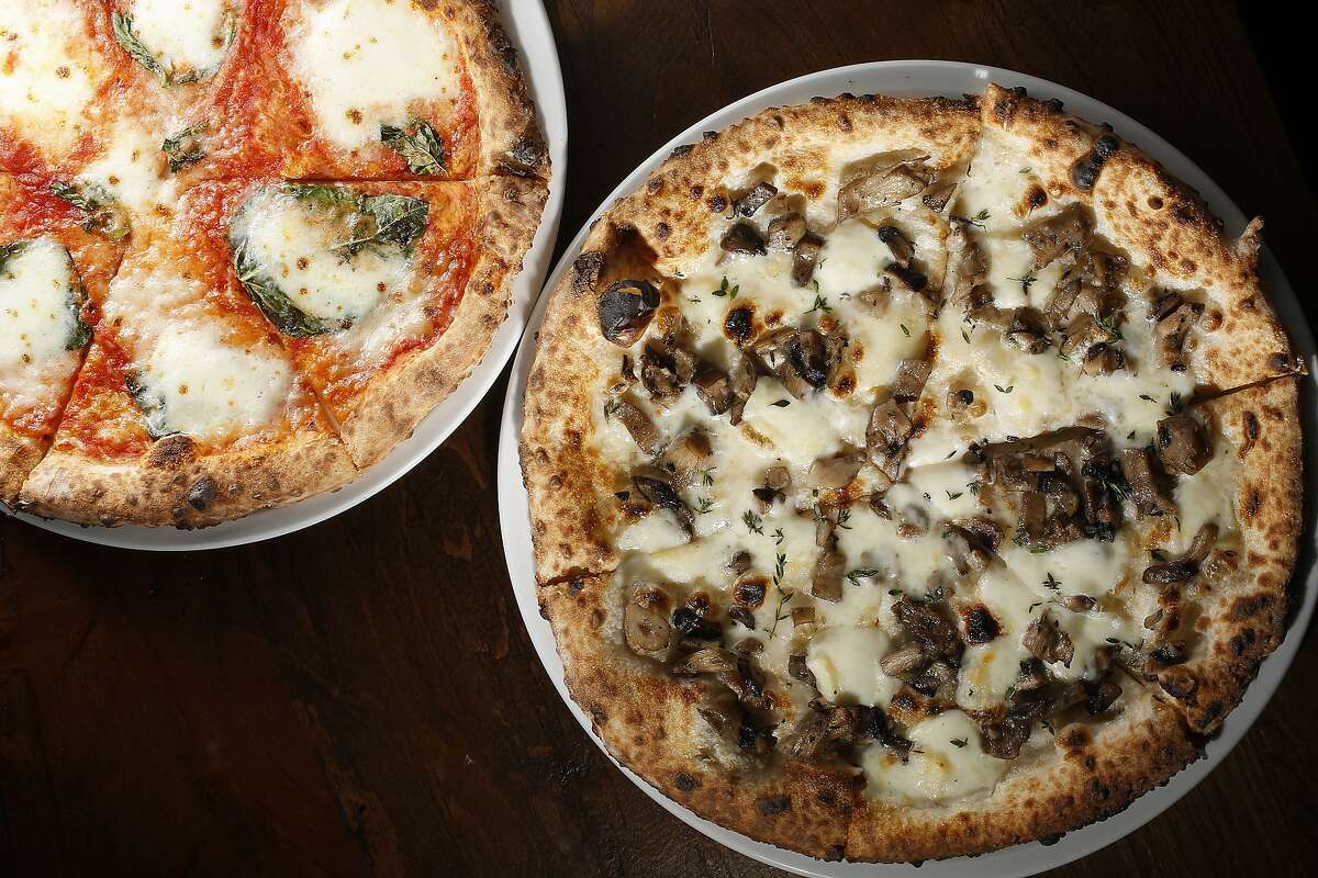 Margherita pizza (left)--house-made Fior Di Latte, basil, San Marzano tomato, olive oil--and Funghi pizza (right)--roasted local mushrooms, thyme, fontina, taleggio--are part of the menu at Caputo in San Francisco, California, on Friday, December 4, 2015.