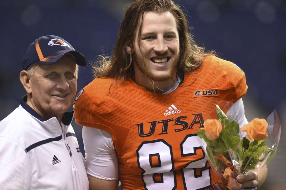 UTSA senior tight end David Morgan II carries flowers as he stands with coach Larry Coker before the team's game against Middle Tennessee State in college football action in the Alamodome on Saturday, Nov. 28, 2015.