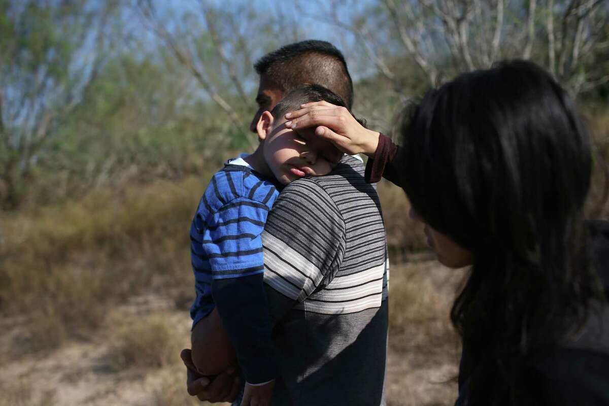 RIO GRANDE CITY, TX - DECEMBER 07: A mother shields the face of her son's from the sun, as her husband carries their sleeping boy, 3, after their family illegally crossed the U.S.-Mexico border on December 7, 2015 near Rio Grande City, Texas. The father said he was bringing his family from Guanajuato, Mexico to settle in San Antonio, Texas. They were detained by the U.S. Border Patrol not far from the Rio Grande, which forms the border betweeen the U.S. and Mexico in Texas. The number of migrant families and unaccompanied minors crossing the border has surged in recent months, even as the total number of illegal crossings nationwide has gone down from the previous year. (Photo by John Moore/Getty Images)