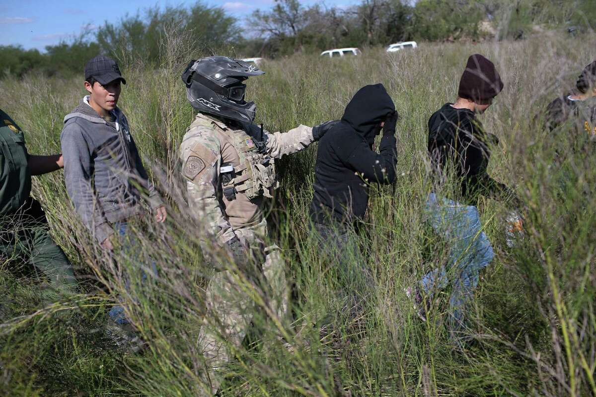 RIO GRANDE CITY, TX - DECEMBER 07: A U.S. Border Patrol agent leads undocumented immigrants after capturing them near the U.S.-Mexico border on December 7, 2015 near Rio Grande City, Texas. Border Patrol agents continue to detain hundreds of thousands of undocumented immigrants trying to avoid capture after crossing into the United States, even as migrant families and unaccompanied minors from Central America cross and turn themselves in to the Border Patrol to seek assylum. (Photo by John Moore/Getty Images)