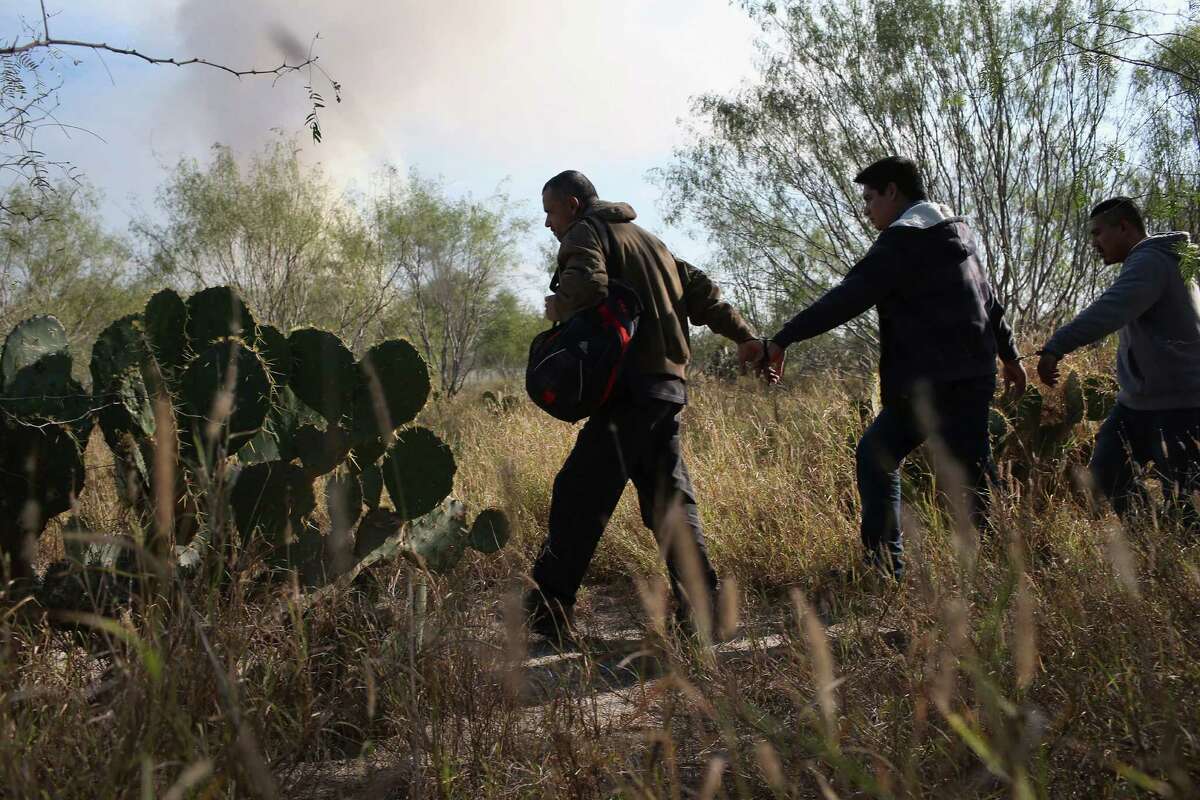 RIO GRANDE CITY, TX - DECEMBER 07: Immigrants walk handcuffed after illegally crossing the U.S.-Mexico border and being caught by the U.S. Border Patrol on December 7, 2015 near Rio Grande City, Texas. Border Patrol agents continue to capture hundreds of thousands of undocumented immigrants, even as the total numbers of those crossing has gone down. (Photo by John Moore/Getty Images)