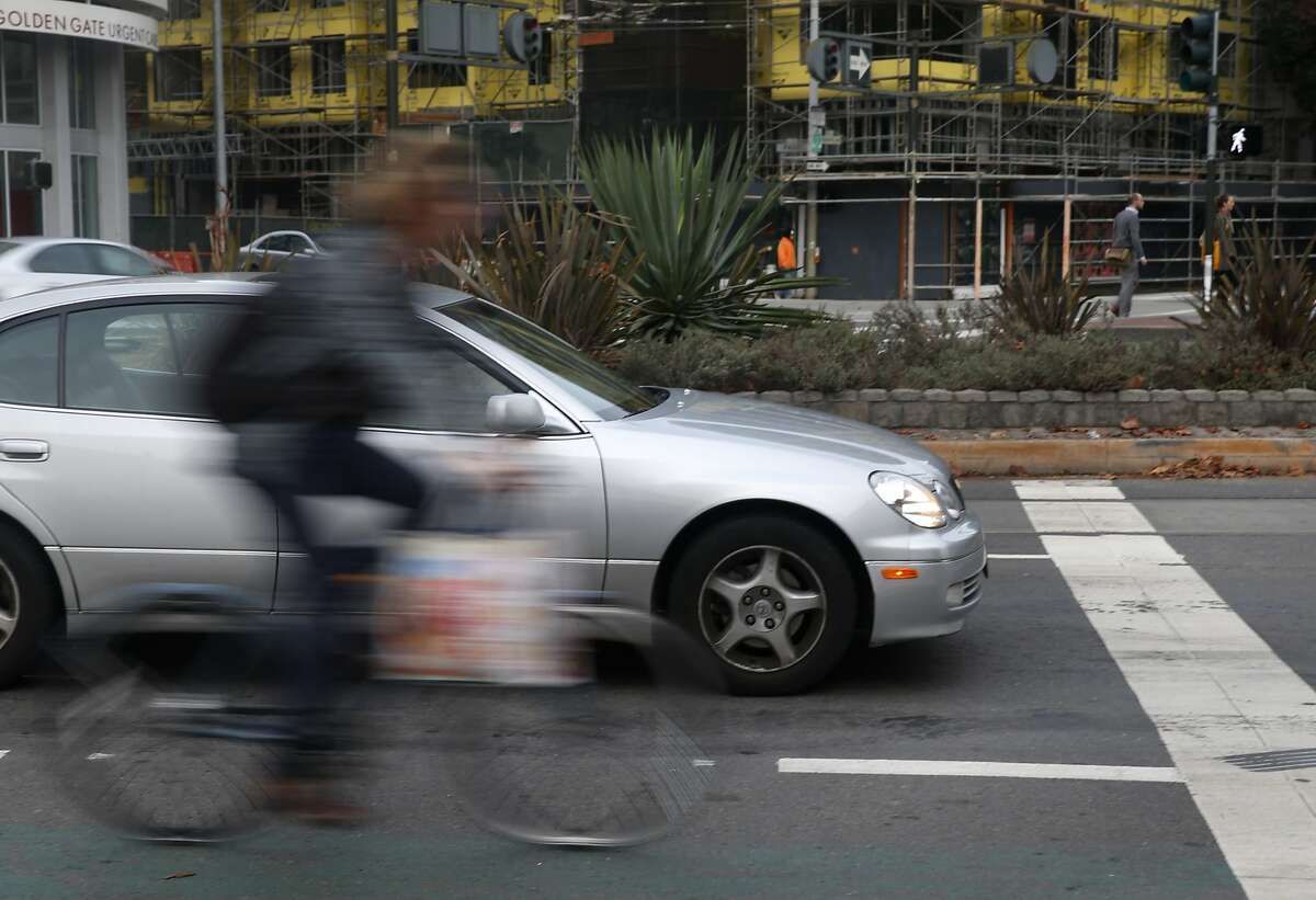 A bicyclist rides past cars stopped for a red light on Market Street near Gough Street in San Francisco. Supervisor John Avalos is moving forward with his proposal to permit bicyclists to roll through stop signs, a plan that Mayor Ed Lee says he would veto.