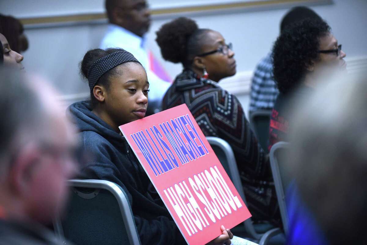A young woman holds a sign supporting Willis Mackey during a special meeting called by the Judson ISD's board of trustees on Wednesday, Dec. 9, 2015. The board and the public discussed rescinding the naming of the district's new high school after former superintendent Willis Mackey, who took a buyout and is still on the district's payroll.