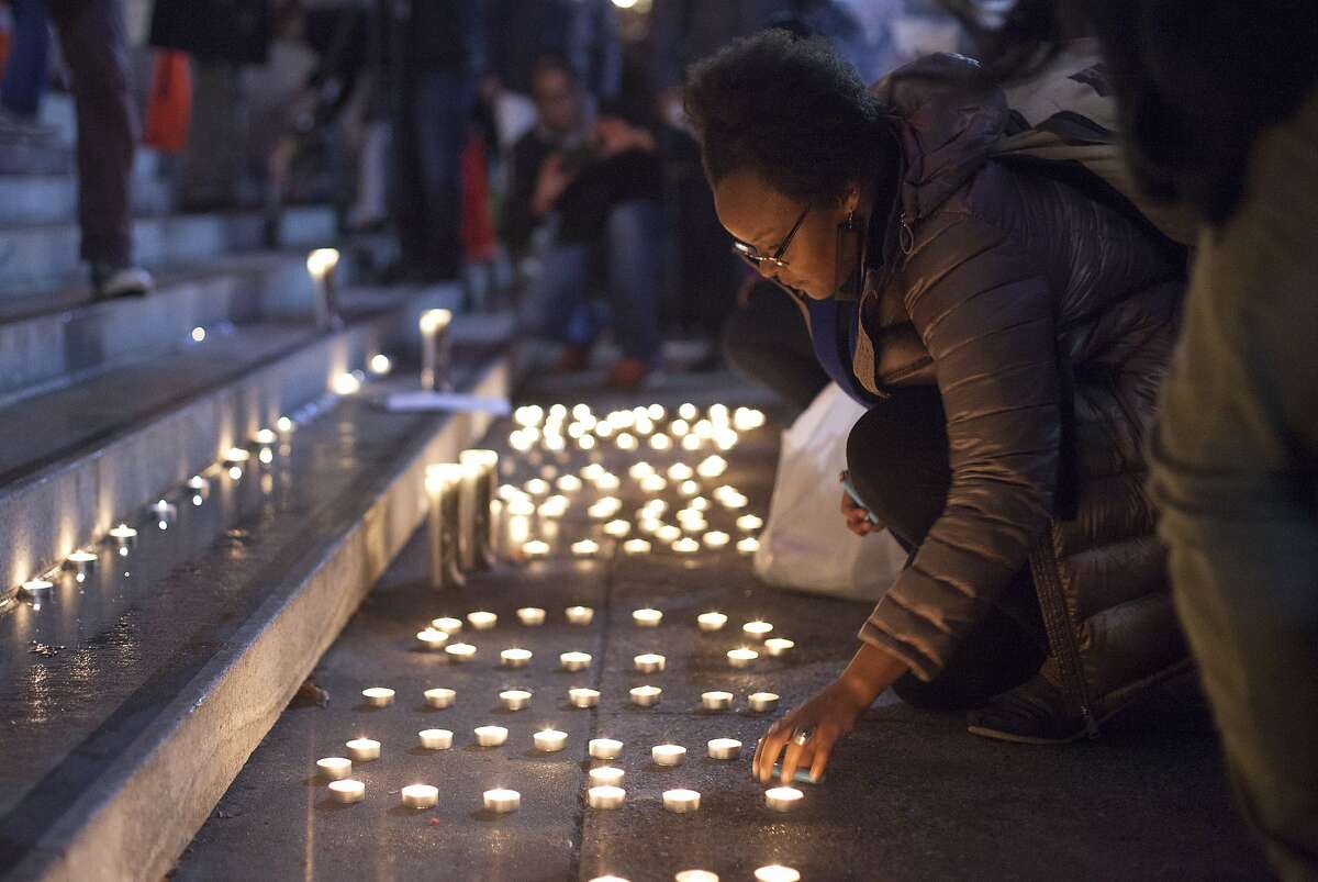 Brittany Moore, a Black Lives Matter member, lights candles outside San Francisco City Hall, Wednesday, Dec. 9, 2015, in San Francisco, Calif. The S.F. Police Commission met inside City Hall and talked about the possibility of equipping police officers with Tasers following the fatal shooting of Mario Woods. It's a proposal that was turned down twice by the commission in recent years. Woods' case has brought the proposal back. Woods was shot and killed by police officers after police say Woods was armed with a knife and walked toward officers.