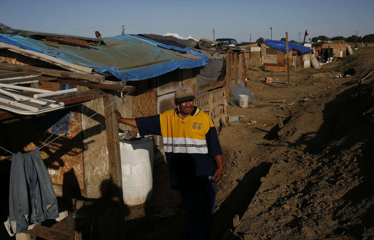 Martín Hernandez Mena, 50, leans against a home he built himself in a shantytown in a dried up canal bed on Westlands Water District land  on the outskirts of Mendota, Calif.