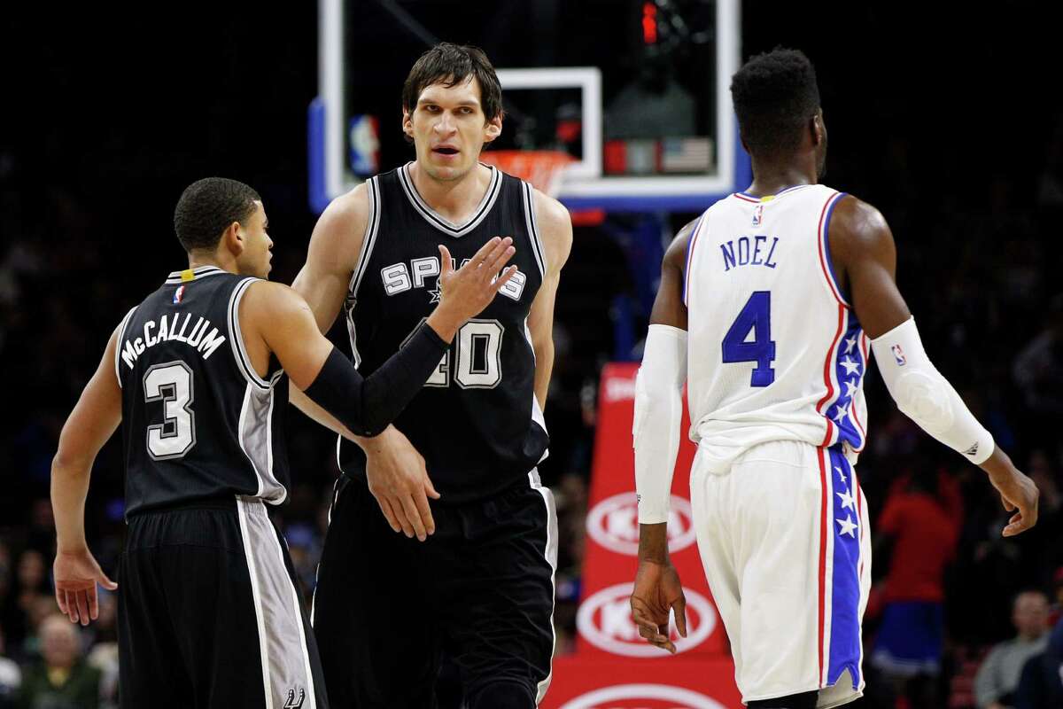 Spurs’ Boban Marjanovic (center) reacts with Ray McCallum as Philadelphia 76ers’ Nerlens Noel heads back to the bench during the second half on Dec. 7, 2015, in Philadelphia.