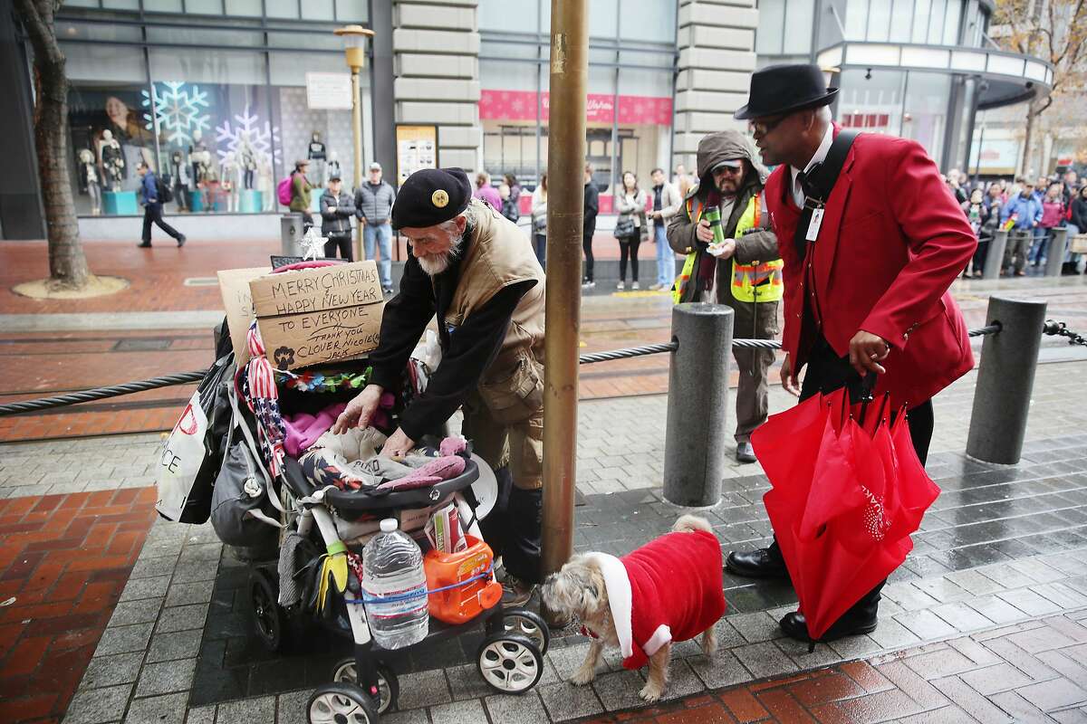 Wayne Alexis (right), Union Square ambassador, talks with Jack Hill (left), who is homeless, at the corner of Powell and Market Streets at the cable car turnaround as Hill prepares to put his dog Clover Nicole (center) into a stroller on Wednesday, December 9, 2015 in San Francisco, Calif.