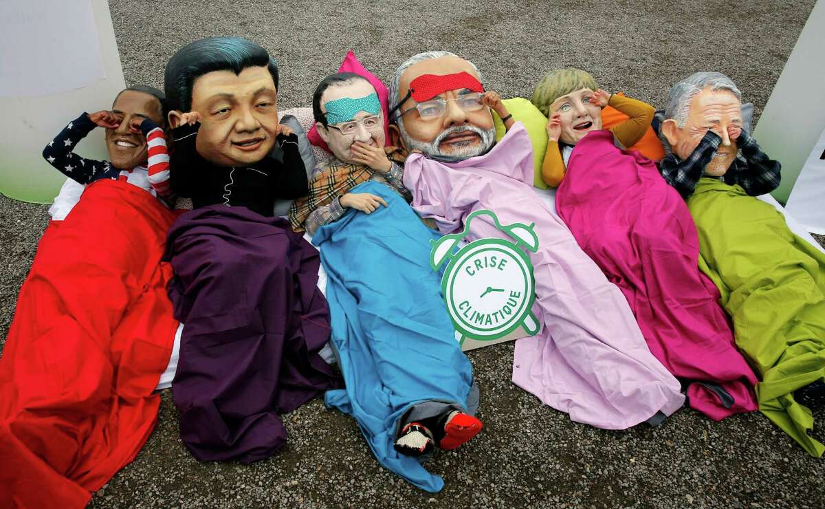 Oxfam activists act out the proverb "see no evil, hear no evil, speak no evil" while wearing masks of﻿ world leaders during a protest Thursday at the climate conference.