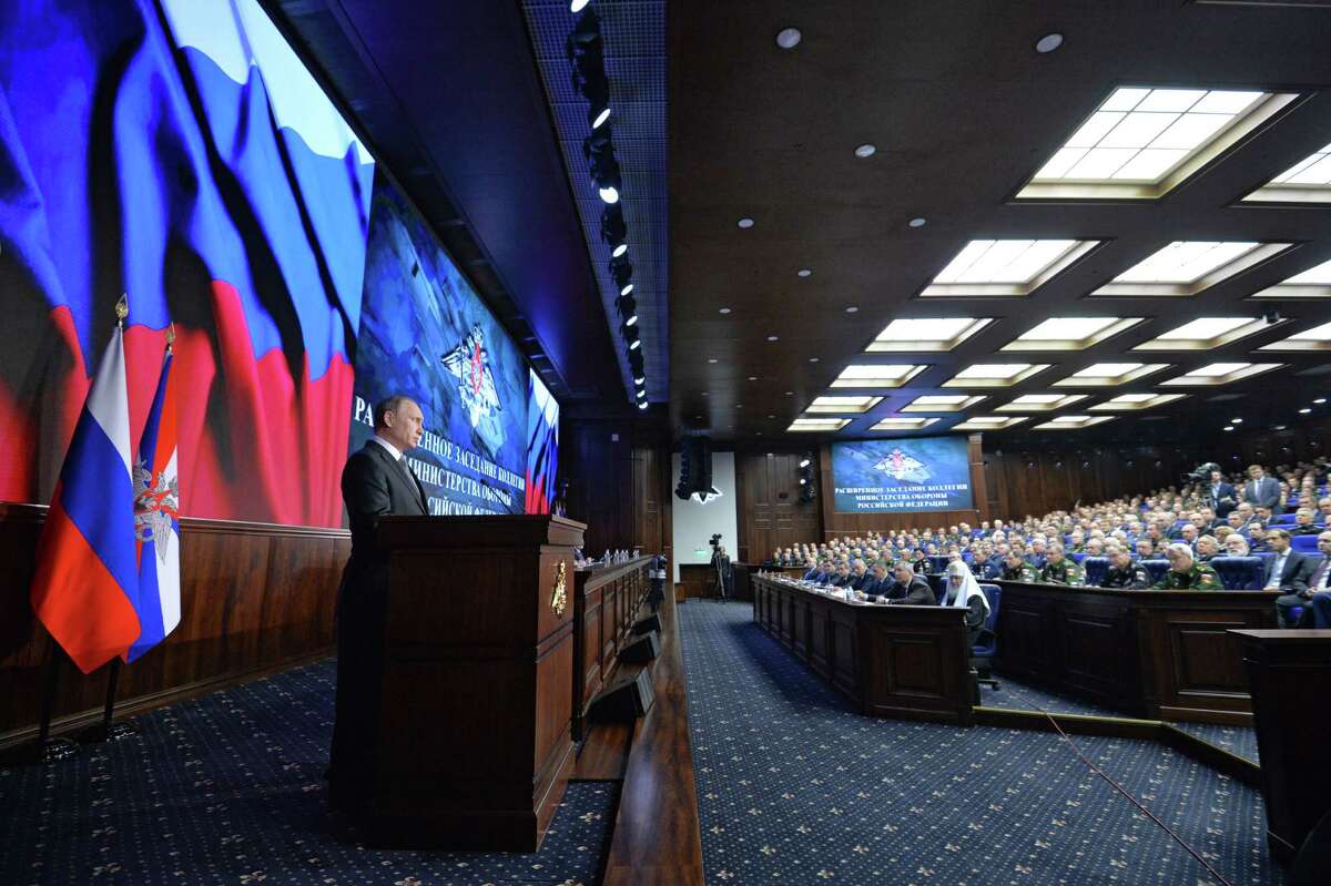 Russian President Vladimir Putin, left, delivers his speech during a meeting with top military officials in Moscow, Russia, Friday, Dec. 11, 2015. Putin said the Russian military action helped change the situation in Syria, supporting the Syrian army offensive. (Alexei Druzhinin, Sputnik, Kremlin Pool Photo via AP)