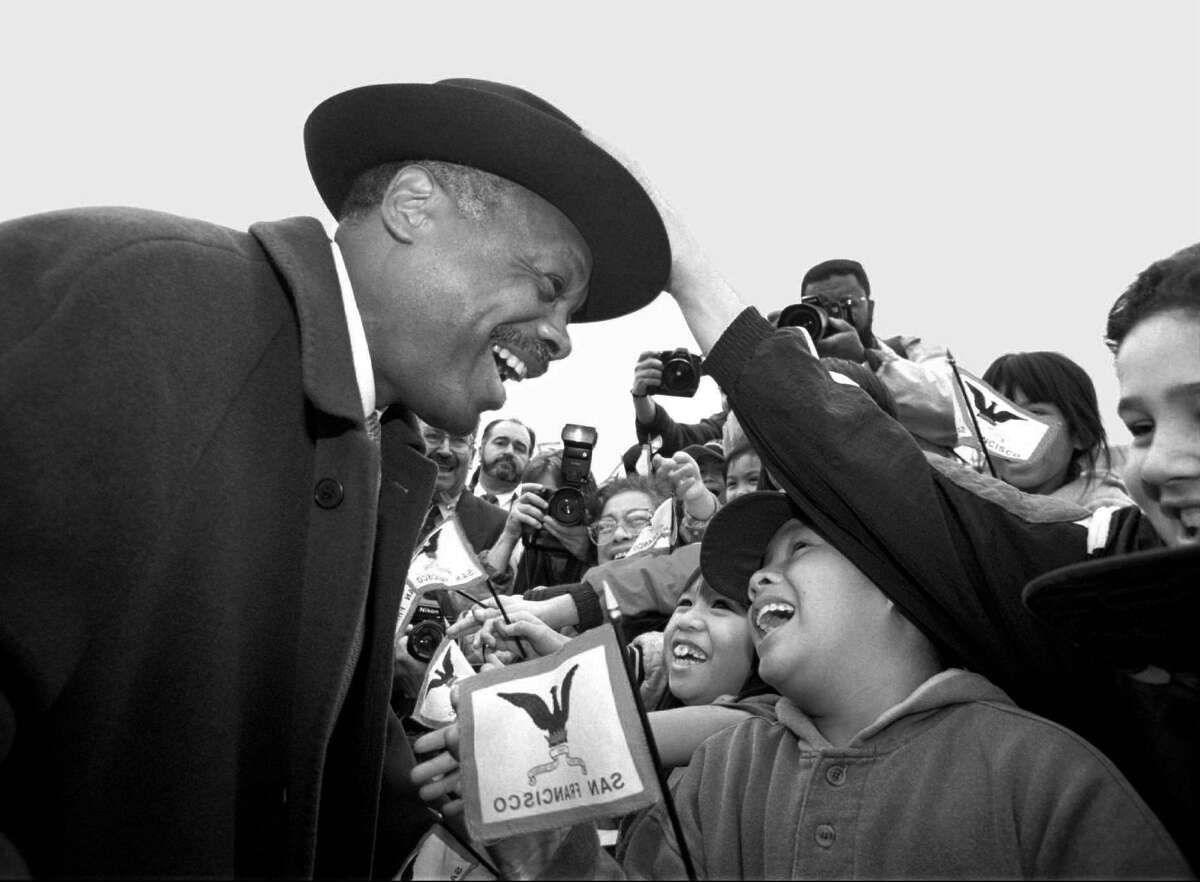 1996年，旧金山市长当选人威利·布朗走进芳草地花园参加落成典礼时，学生们伸出手来欢迎他。前景中的国旗图像没有反转;从后面看。